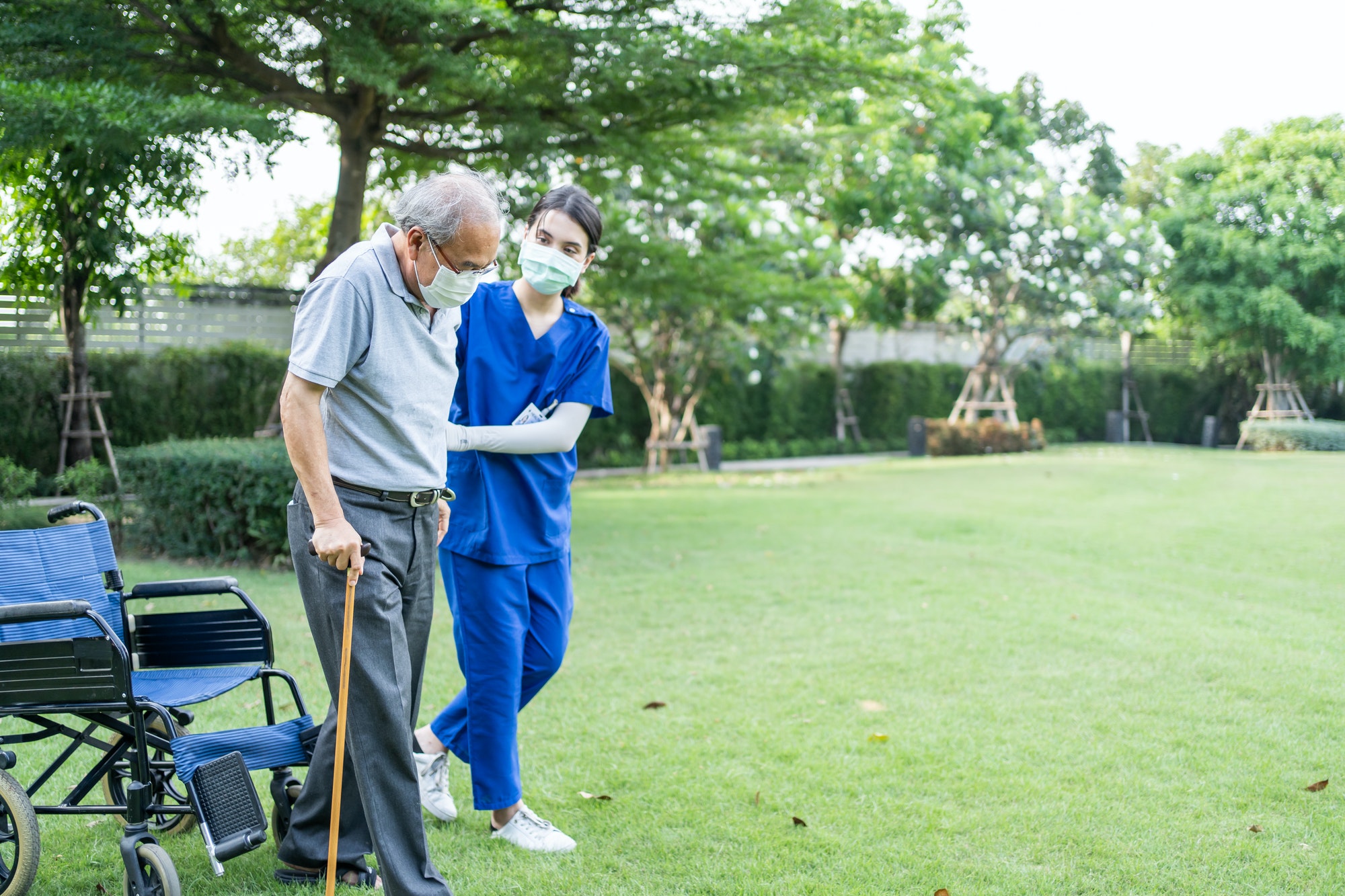 Asian woman nurse take care and support disabled senior elder man on walker or cane at backyard