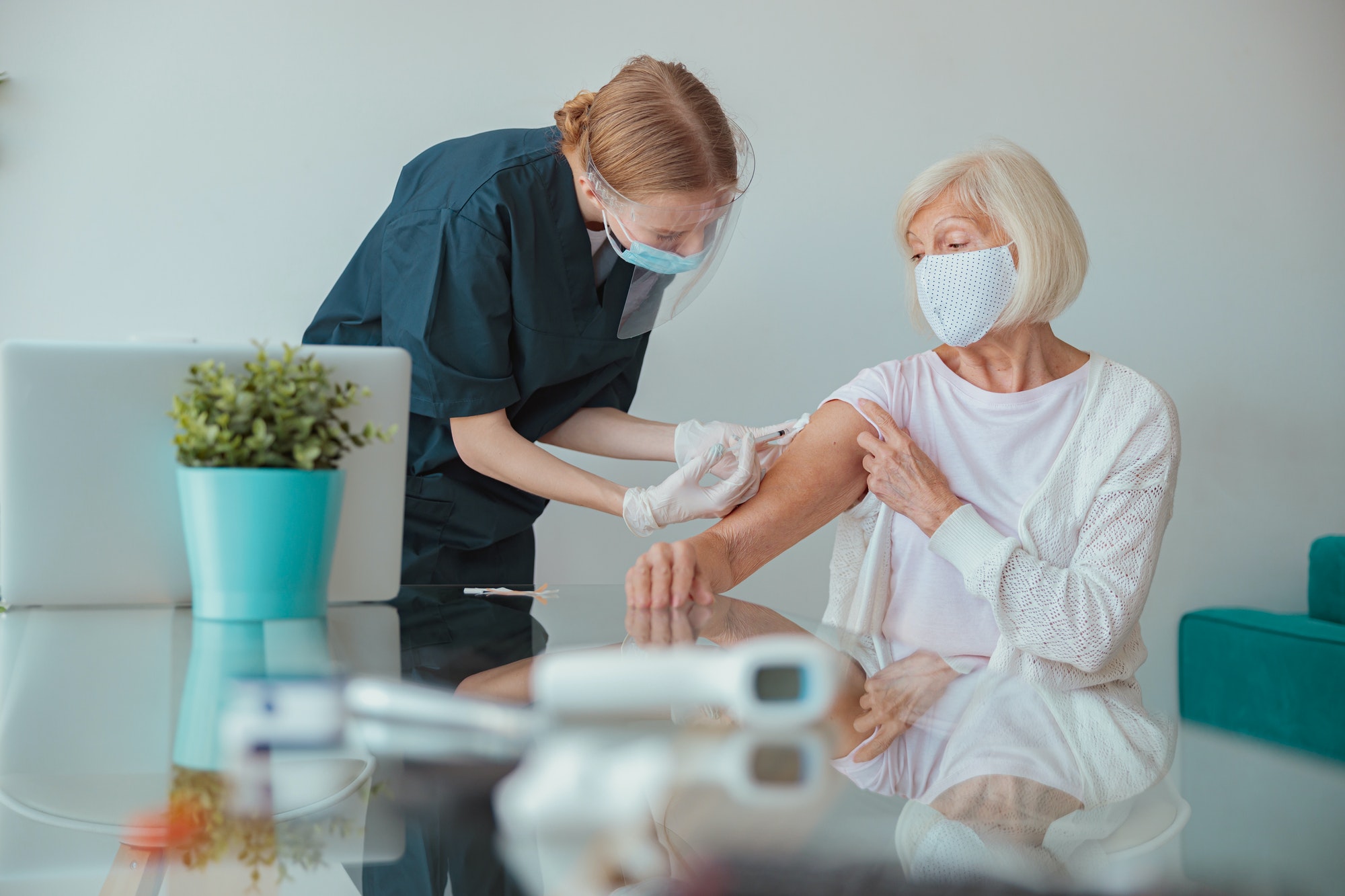 Nurse giving injection to senior woman in living room